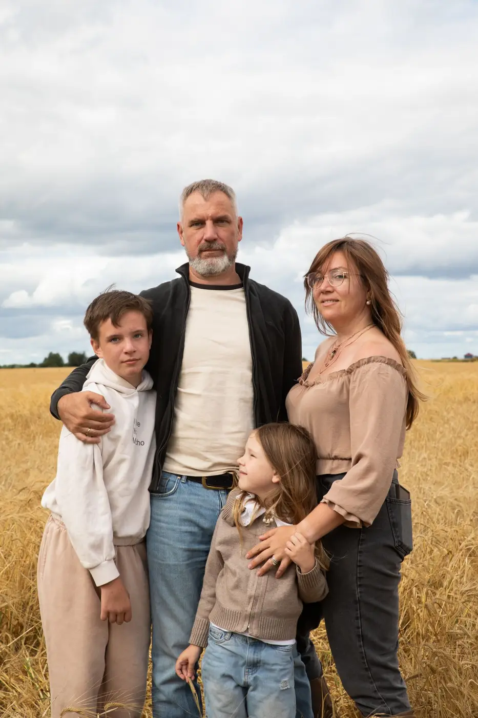 Family of four standing together in a wheat field