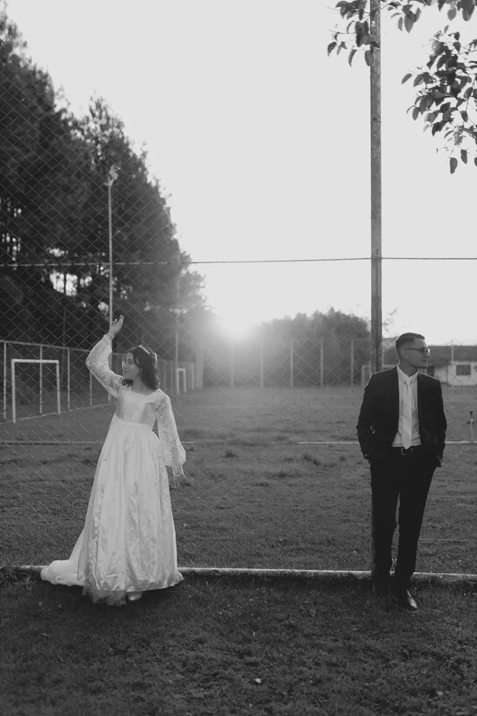 Bride and groom standing in a grassy field at sunset